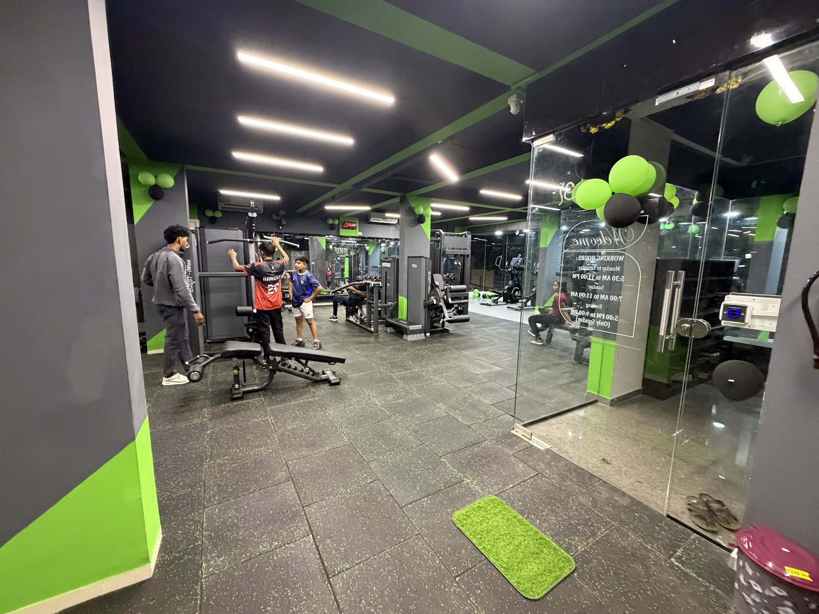 Members training on the main floor at 11:11 Fitness, with the branded entrance door visible in the background