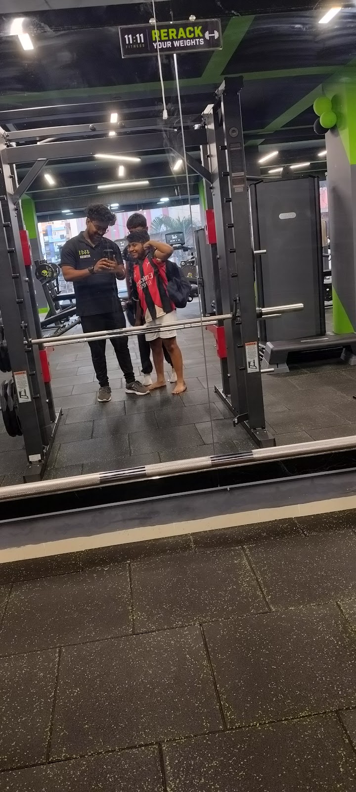 Member at the Smith machine with the 11:11 Fitness wordmark visible on a wall sign in the mirror